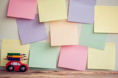 Okul arka plan minyatür kırmızı araba taşıma ile renkli kalemler üzerinde renkli stikers duvara dönün