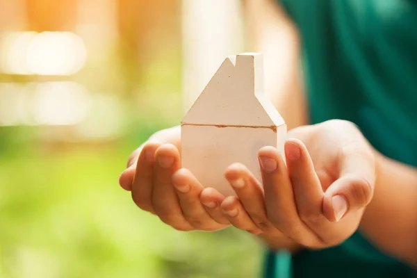 Hands holding wooden house model. Buying a new home and house insurance concept