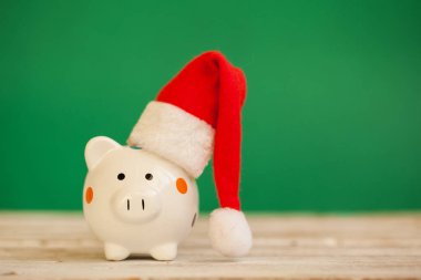 Yeşil zemin üzerine santa claus şapka ile Piggy banka. Noel ve yeni yıl kavramı