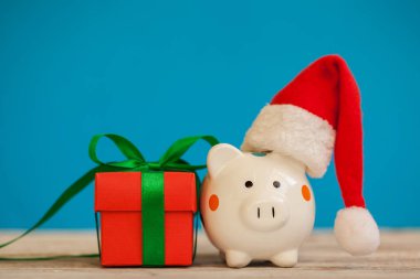 Noel hediye kutusu üzerinde mavi arka plan ile santa claus şapka ile Piggy banka