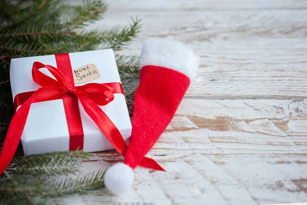 ホワイト クリスマス ボックスまたは木製のテーブルにサンタ帽子をサンタの赤いリボンをプレゼント — ストック写真