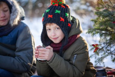 Portre gülümseyen çocuk açık havada güneşli bir günde çikolata içme bir kış yürüyüş.