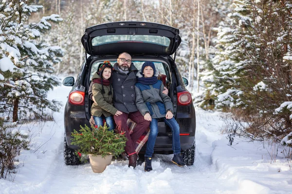 Happy family in black car at snowly winter day.