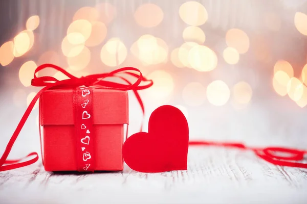 Red box with red paper heart on wooden table. Valentines day greeting card and love concept.