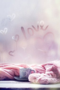 Cup of tea, coffee, chocolate and pink plaid on foggy window with love text. Valentine Day and Love concept.