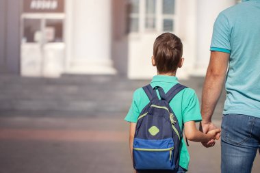 Babası kablolar küçük bir çocuk okul çocuk el ele gidiyor. Anne-baba ve oğlu ile arkadan sırt çantası