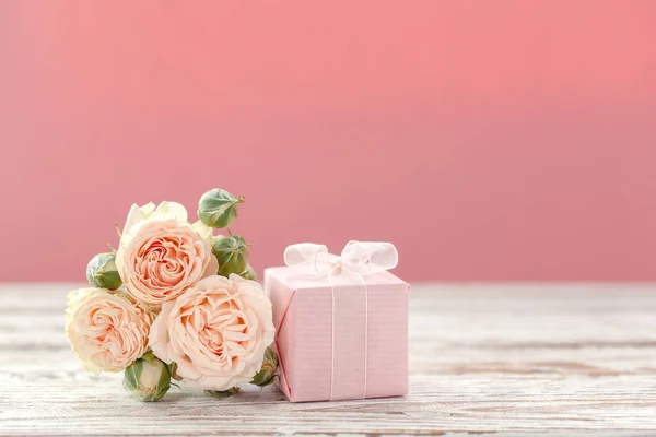 Pink roses flowers and gift or present box pink background. Mothers Day, Birthday, Valentines Day, Womens Day, celebration concept. Space for text.