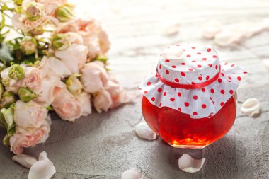 Gül yaprakları bir masada ev yapımı reçel gül buketi ile.