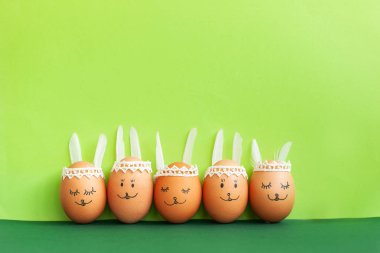 Komik Paskalya tavşanları yumurta üzerinde yeşil kağıt arka plan kopya alanı ile. Mutlu Paskalya kavramı.