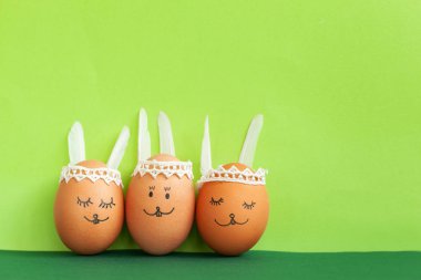 Komik Paskalya tavşanları yumurta üzerinde yeşil kağıt arka plan kopya alanı ile. Mutlu Paskalya kavramı.