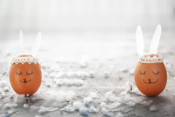 Украшенные Пасхальные Яйца Милые Кроличьи Уши Сером Столе Белыми Перьями — стоковое фото