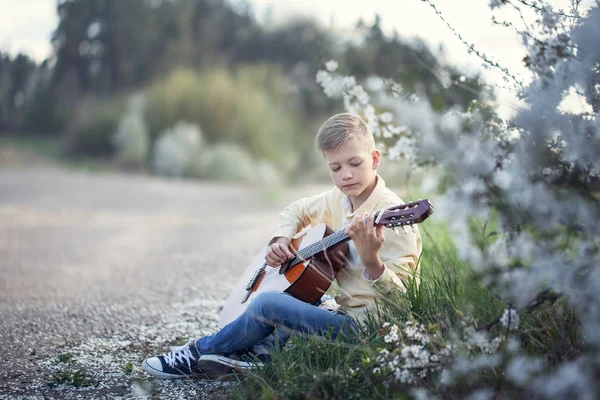 Vacker tonåring med gitarr som sitter på gräset i parken. — Stockfoto