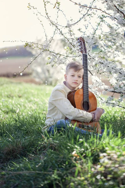 Vacker tonåring med gitarr som sitter på gräset i parken. — Stockfoto