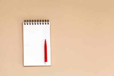 Boş spiral defter masada kırmızı kalem ile. Üstten Görünüm