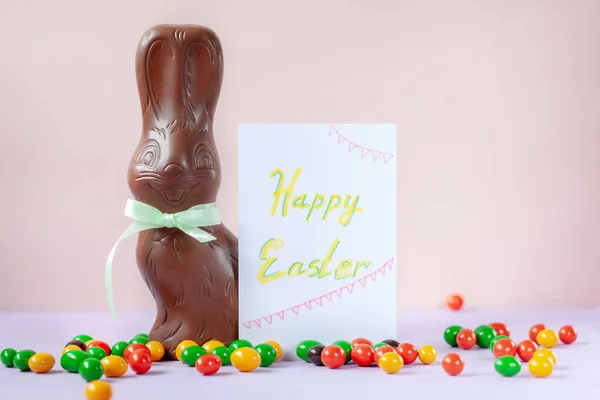 Chocolate conejito de Pascua con tarjeta sobre fondo rosa feliz concepto de Pascua . —  Fotos de Stock