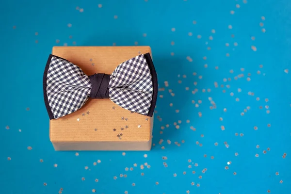 Одна подарункова коробка, загорнута в ремісничий папір і зав'язана краваткою на синьому фоні . — стокове фото