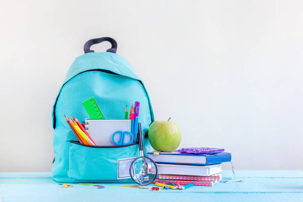 Full turquoise School Backpack with stationery on table.
