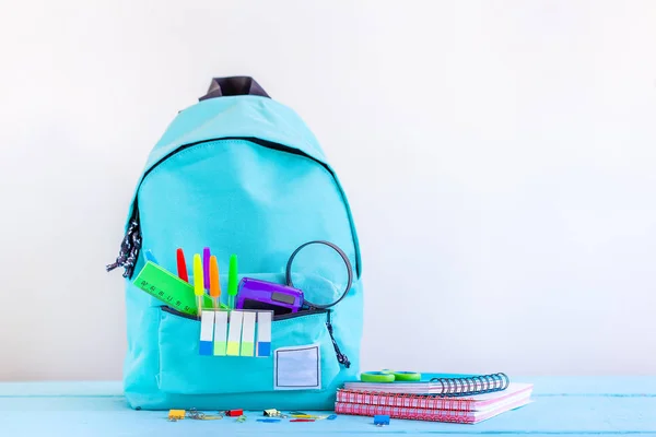 Türkisfarbener Schulrucksack mit Schreibwaren auf dem Tisch. — Stockfoto