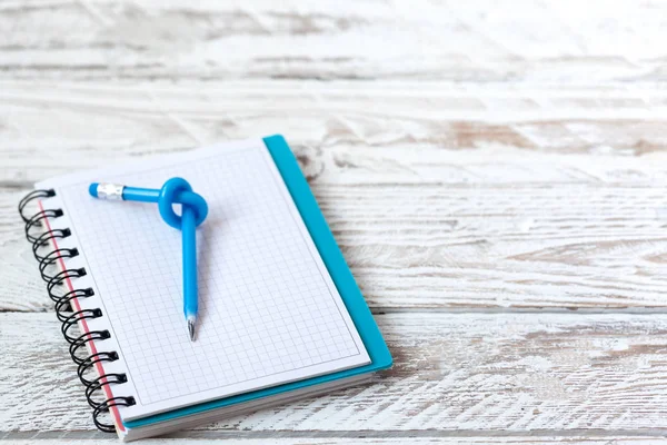 Blue Pencil with knot on writing pad on white wood background.