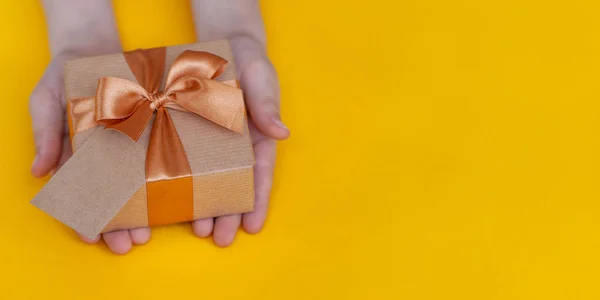 Kinderen handen Holding present box op gele achtergrond. — Stockfoto