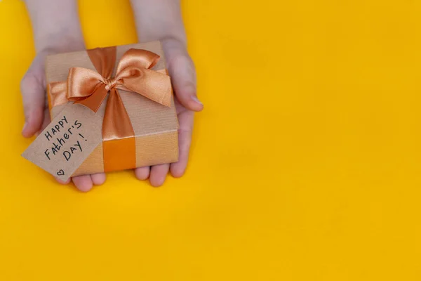 Happy Fathers Day concept. Kinderen handen Holding present Box voorvader op gele achtergrond. — Stockfoto
