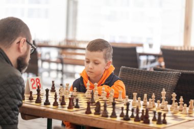 Çocuk bir okulda aile Satranç Turnuvası babası ile satranç oynuyor.