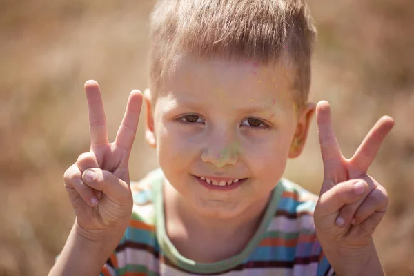 Fresco ragazzo pieno di polvere colorata su tutto il viso . — Foto Stock