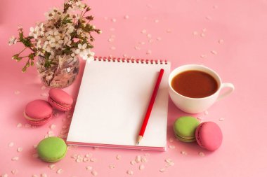 Temiz defter ve fransız renkli macaroons kahve fincan ile, pembe arka plan üzerinde yalan.