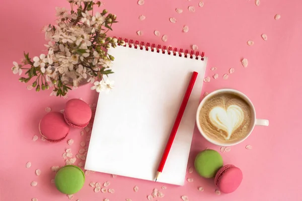 Sauberes Notizbuch und französische bunte Makronen mit Tasse Kaffee, auf rosa Hintergrund liegend. — Stockfoto