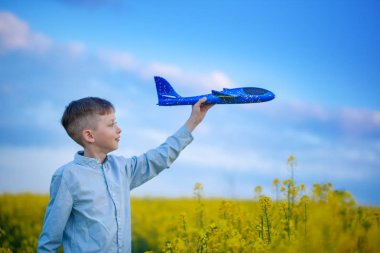 Sevimli çocuk mavi gökyüzünde bir oyuncak uçak ve seyahat hayalleri ile oynar. Mavi oyuncak düzlemile el.
