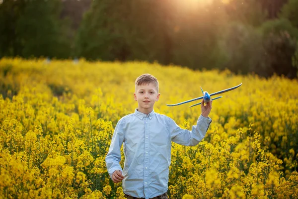 Adorable Boy trzyma samolot zabawka w ręku na zachodzie słońca w letni dzień. — Zdjęcie stockowe