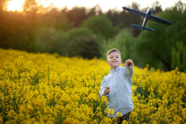 Boy throwing toy airplane in summer day on sunset. — Stock Photo, Image