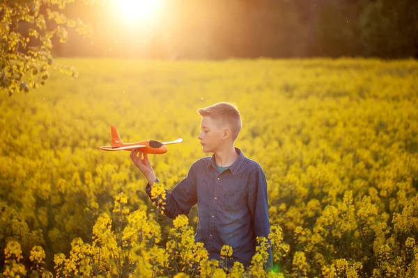 Dziecko gra z samolotu zabawka w zachodzie słońca i marzenia o podróży w letni dzień. — Zdjęcie stockowe