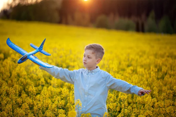 Criança brinca com um avião de brinquedo ao pôr do sol e sonha com a viagem no dia de verão . — Fotografia de Stock
