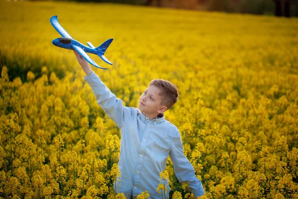 Bambino gioca con un aeroplano giocattolo al tramonto e sogni di viaggio in giorno d'estate . — Foto Stock