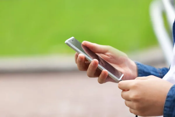 Junger Mann mit Smartphone im Freien. Teenager hält das Telefon in der Hand. — Stockfoto