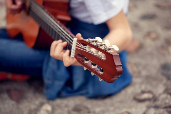 Joven sosteniendo una guitarra y tocando música. Enfócate en la cabeza de la guitarra de seis cuerdas . —  Fotos de Stock