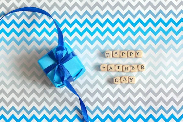 Щасливий день батька вітальна листівка з прикрашеною синьою подарунковою коробкою на зигзагоподібному смугастому фоні. Вид зверху . — стокове фото
