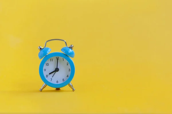 黄色の背景に青い目覚まし時計。ミニマリズム。コントラストの概念. — ストック写真