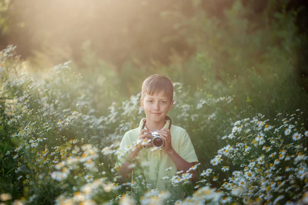 Süße junge Fotograf schießt mit der Kamera in der Natur. Kind macht ein Foto im Kamillenblütenfeld. — Stockfoto