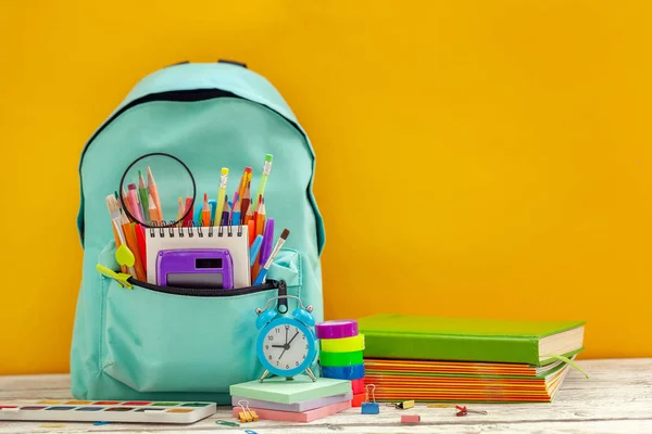 Повний шкільний рюкзак з різними приладдям на помаранчевому фоні. Концепція повернення до школи . — стокове фото