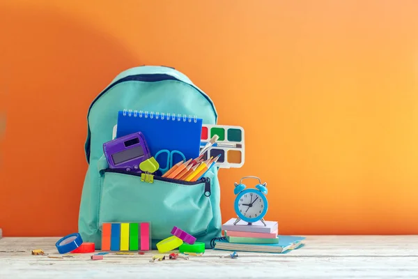 Mochila de escuela completa con diferentes suministros sobre fondo naranja. Concepto de regreso a la escuela . —  Fotos de Stock