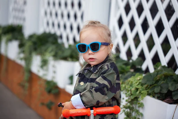 Крутая стильная девочка в солнцезащитных очках на скутере на улице . — стоковое фото