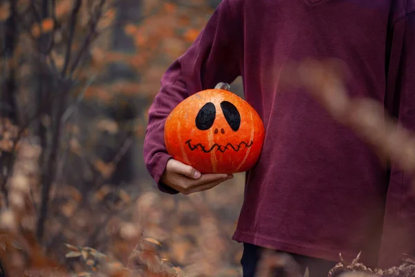 Menino segurando nas mãos uma abóbora assustadora de Halloween . — Fotografia de Stock