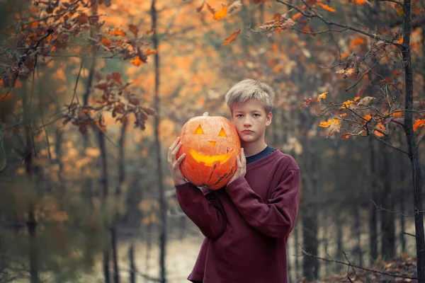 Jóképű fiú pózol a parkban halloween tök. — Stock Fotó