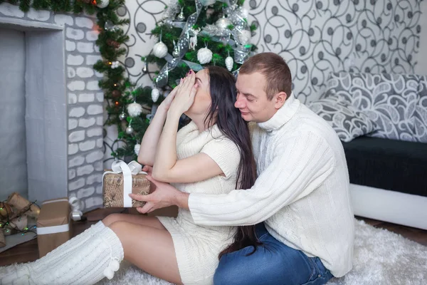 Junge Frau bedeckt ihre Augen mit Hand und Mann schenkt Weihnachtsüberraschung. — Stockfoto