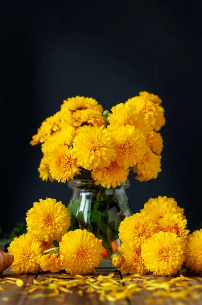 Ramo de hermosos crisantemos amarillos sobre mesa de madera sobre fondo negro. —  Fotos de Stock