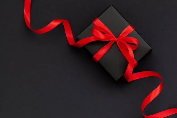 Концепція Чорної п'ятниці. Вид зверху чорної подарункової коробки з червоною стрічкою на чорно-червоному тлі з місцем для тексту . — стокове фото