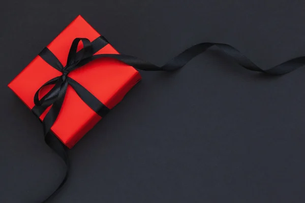 Червона подарункова коробка з чорною стрічкою на чорному тлі з місцем для тексту . — стокове фото