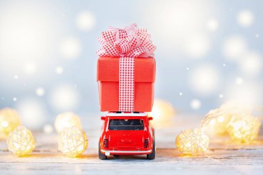 Kırmızı oyuncak araba, arka planda çatıda hediye kutusu taşıyor. Noel ve yeni yıl konsepti. Arka plan.